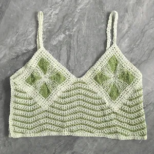 Close-up of a handmade crochet camisole featuring green floral motifs and wavy patterns.