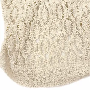 Detailed macro view of geometric diamond crochet hollow-out pattern on apricot knit vest