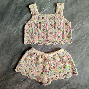 Detailed look at colorful embroidered floral patterns on a white crochet knit two-piece set