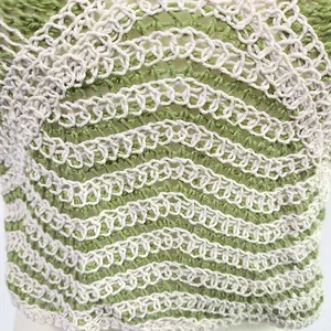 Macro view of the wavy green and white crochet pattern on this breathable cotton top