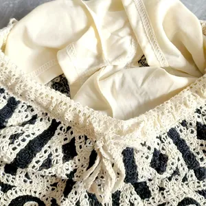 Close-up of cream and black crochet knitted shorts with intricate openwork lace and tie detail