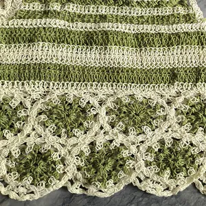 Gros plan sur un tricot au crochet vert et crème avec motifs floraux et bords festonnés