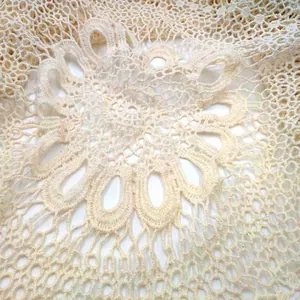 Close-up view showing the intricate cream cotton crochet lace pattern of a beach vest.