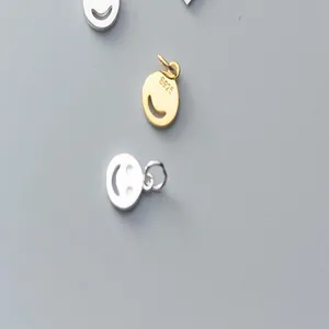 Detailed view of S925 sterling silver and gold plated smiley face charms for DIY jewelry.