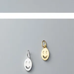 Macro detail of S925 silver and gold-plated smiley face pendants for DIY jewelry making.