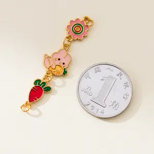 Detail view of colorful enamel rabbit and carrot charm chain with coin for scale