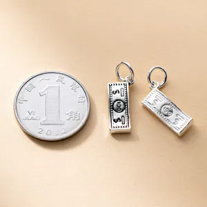 Detailed view of S925 silver 100 dollar bill charms with a coin for size reference