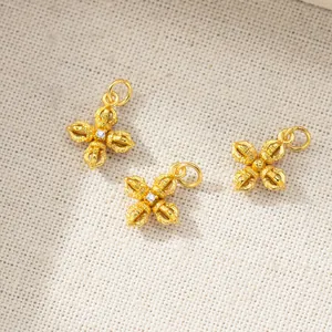 Close-up of three golden vajra cross charm pendants on white linen cloth texture