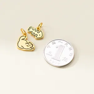Close-up of cute gold-plated silver cat and fishbone charms with coin for scale