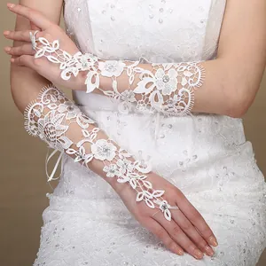 Dettaglio di eleganti guanti da sposa in pizzo bianco con decorazioni di strass lucidi