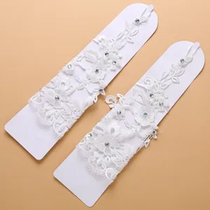 Dettaglio di guanti da sposa in pizzo bianco con delicati strass e motivo floreale.