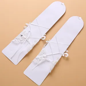 Dettaglio di guanti da sposa in pizzo bianco vintage con lacci e strass