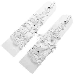 Vista dettagliata di guanti da sposa in pizzo bianco con decorazioni in strass brillanti.