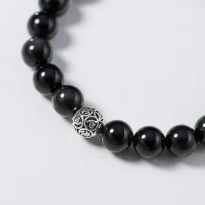 Close-up detail of a black obsidian beaded bracelet featuring a carved S925 silver bead accent.
