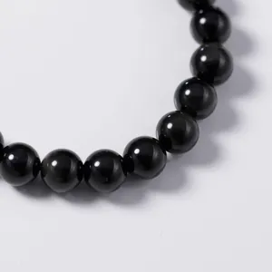 Close-up of glossy black obsidian beads on a minimalist handcrafted beaded bracelet