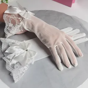 Dettaglio di guanti da sposa in pizzo bianco con eleganti fiocchi di raso e strass.