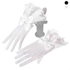 Close-up of white lace bridal gloves featuring a satin bow and heart-shaped rhinestone