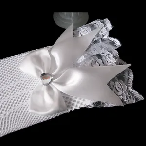 Detailed view of white bridal lace gloves with satin bow and heart-shaped rhinestone