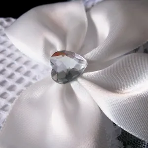 Macro view of white satin bow with heart-shaped rhinestone on lace bridal glove