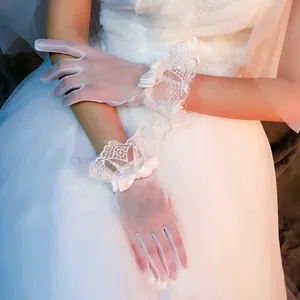 Dettaglio di guanti da sposa in pizzo bianco con fiocco in raso e ricamo floreale