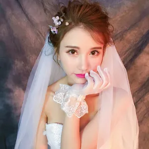 Dettaglio di guanti da sposa in pizzo bianco con eleganti ricami floreali e volant