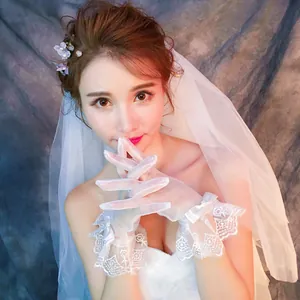 Primo piano di eleganti guanti da sposa in pizzo bianco con fiocchi di raso e ricami