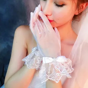 Primo piano dettagliato di guanti da sposa in pizzo bianco con volant e fiocco di raso