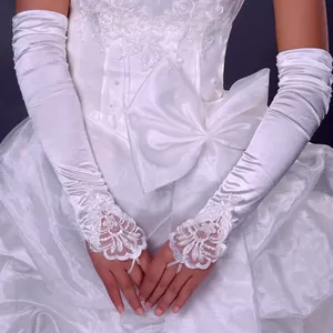 Nahaufnahme von langen weißen Brauthandschuhen aus Satin mit eleganter Spitze und Perlen
