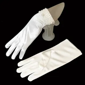 Close-up of white satin bridal gloves with faux pearl beaded cuffs on black background.