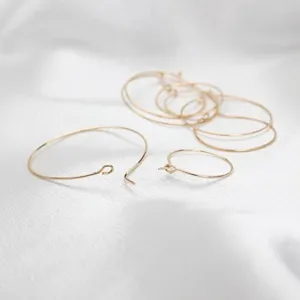 Dettaglio macro di delicati ganci dorati per anelli di bicchieri da vino su tessuto bianco
