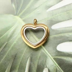 Detail view of a golden stainless steel heart-shaped locket pendant on a green leaf background.