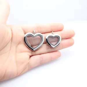 Detailed view of two sizes of stainless steel heart lockets with glass windows on a hand