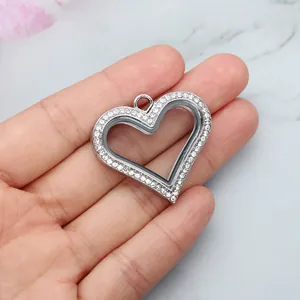 Close-up of silver heart-shaped glass locket pendant with sparkling rhinestones in hand