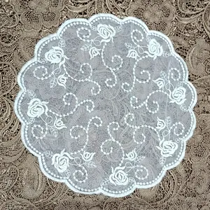 Detailed close-up of vintage round white embroidered lace doily with rose motifs