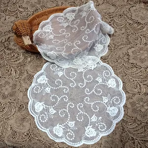 Macro detail of white embroidered lace coaster doily with vintage floral rose pattern.