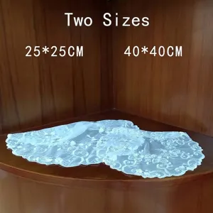 Detail view showing two sizes of white embroidered floral lace doilies on wood shelf