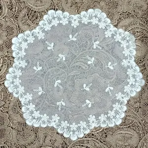 Close-up detail of vintage white lace coaster with delicate floral embroidery on net base