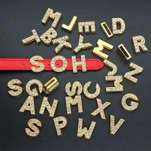 Detailed macro view of 10mm gold rhinestone alphabet charms displayed on a red leather strap
