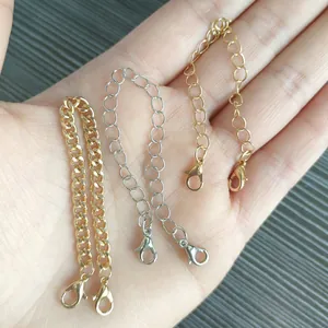 Close-up of gold and silver metal extension chains with lobster clasps held in hand