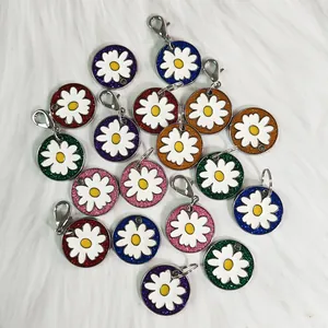 Colorful glitter daisy pet tags scattered on a white fluffy background
