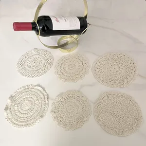 Close-up of six different vintage white crochet lace coasters on a marble table