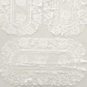 Close-up of elegant white water-soluble lace placemats with intricate rose embroidery