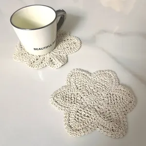 Close-up of a beige crocheted cotton lace coaster in a star shape on marble surface