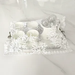 White lace embroidered dust mat detail covering an elegant white ceramic tea set.