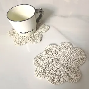 Detailed macro view of a beige hand-crocheted cotton lace coaster with floral petal patterns