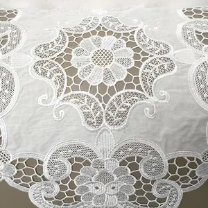 Nahaufnahme eines weiß bestickten Spitzenstoffs mit hohlen Blumen- und Paisleymustern.