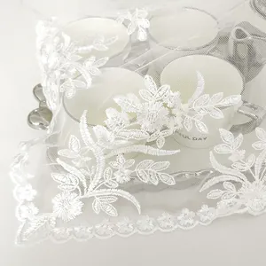 Detailed close-up of exquisite white floral lace embroidery on transparent mesh dust cover