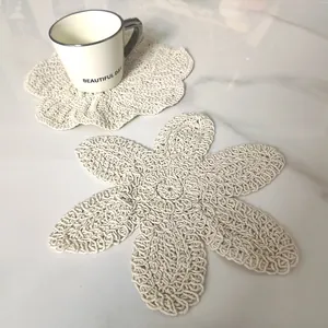 Detail of cream-colored hand-knitted cotton coaster in a vintage flower petal shape