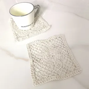Detailed macro shot of vintage beige lace square coaster with floral crochet pattern