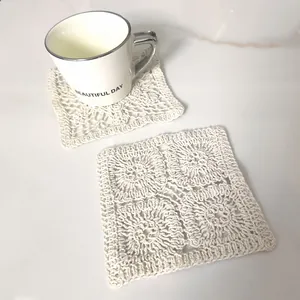 Detailed view of two cream square crocheted cotton coasters on marble background